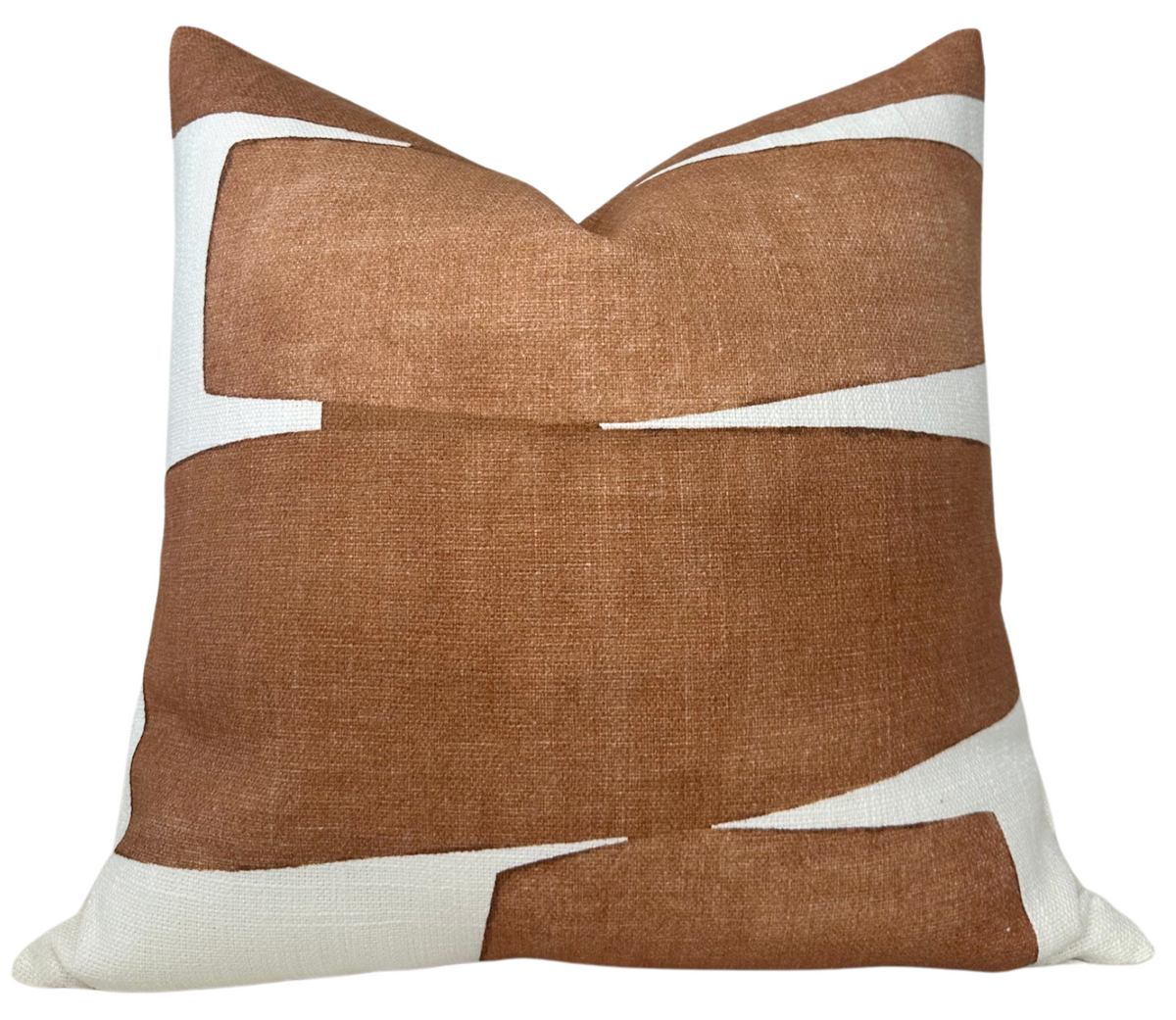 Square pillow with overlapping irregular clay-colored shapes on a white background, creating a modern abstract pattern.