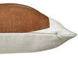 Close-up of a rectangular pillow with a clay brown woven fabric top section and an off-white textured fabric bottom section, featuring a small white zipper on the side.