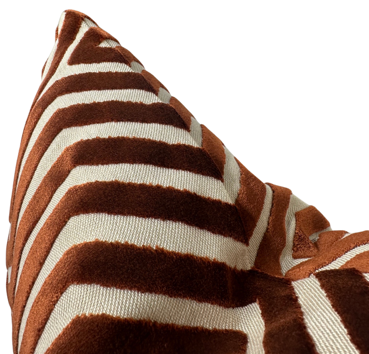 Close-up of a pillow cover featuring a textured rust and cream striped pattern in angular lines, creating a visually dynamic geometric design.