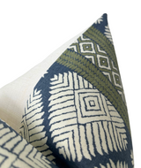 Close-up of pillow corner with geometric patterns in bluestone blue, olive green, and off-white on fabric.