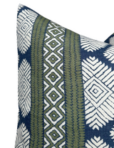 Close-up of a pillow corner featuring a Bluestone blue and white geometric pattern with vertical green stripes decorated by diamond and zigzag designs.