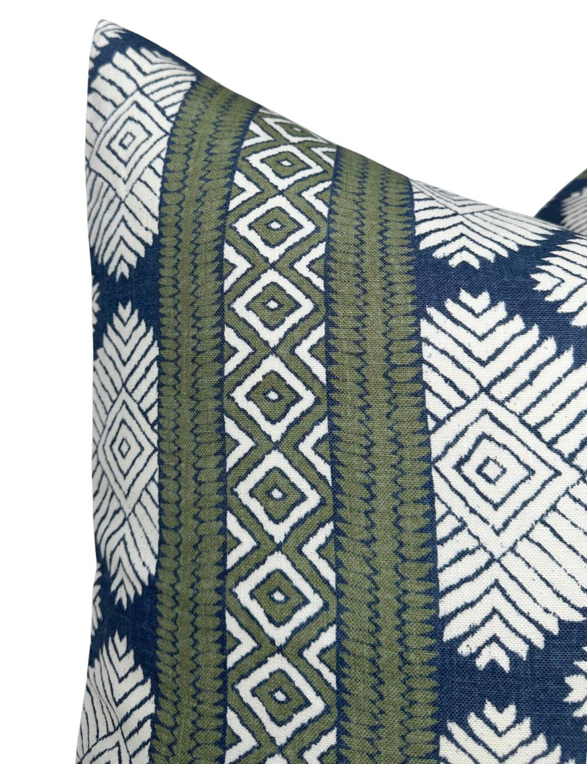 Close-up of a pillow corner featuring a Bluestone blue and white geometric pattern with vertical green stripes decorated by diamond and zigzag designs.
