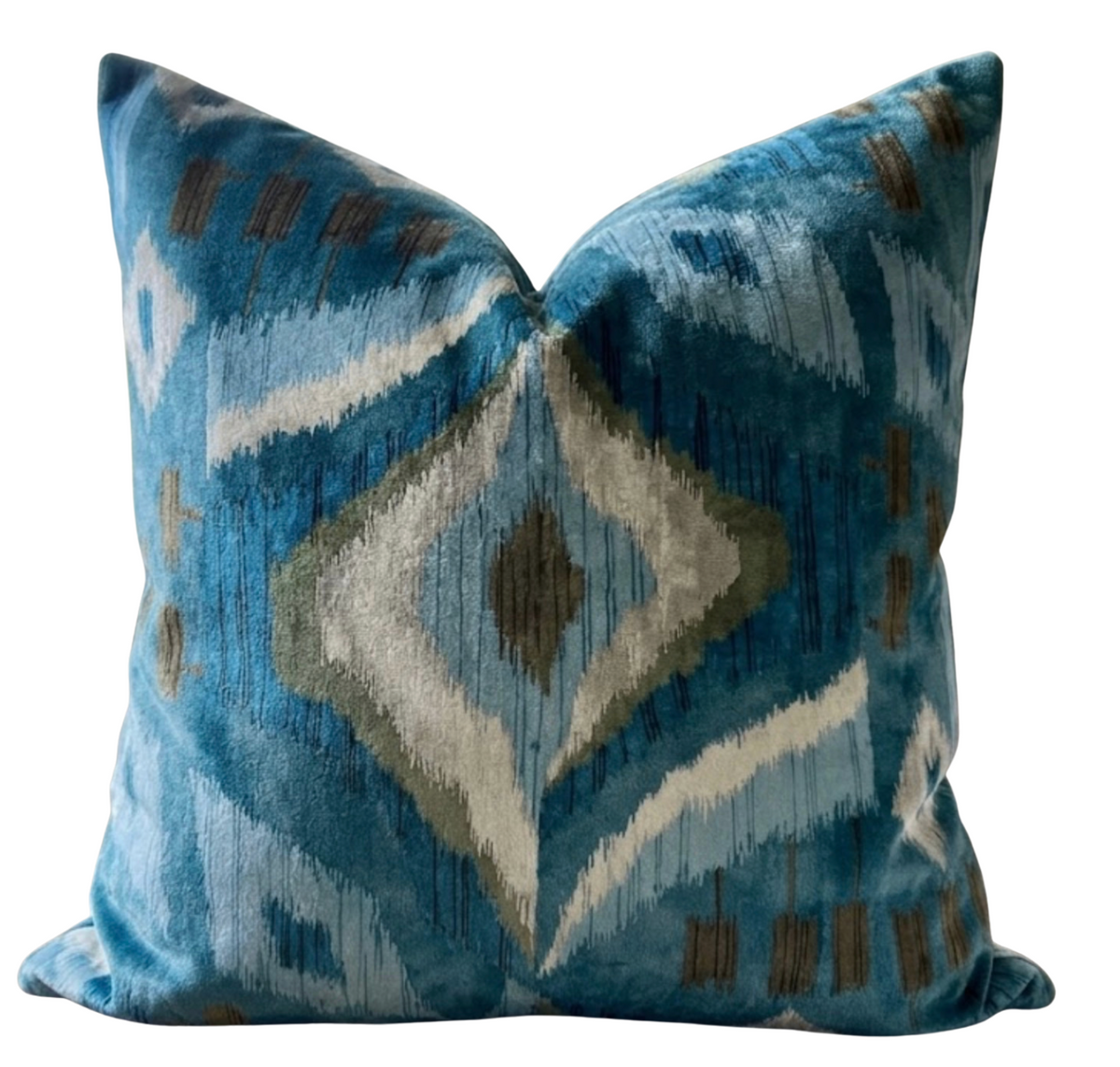 Square velvet pillow with a mineral blue ikat-inspired pattern featuring a central diamond shape and accents of gray, white, and brown.