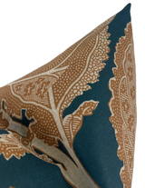 Close-up of a pillow corner featuring an intricate ochre botanical pattern on a deep mineral blue fabric background