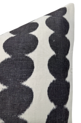 Close-up of a white pillow cover featuring two vertical rows of repeating rounded black shapes with a slightly faded texture on the fabric.