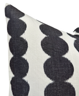Close-up of a pillow cover featuring a pattern of large black circular shapes linked vertically on a white textured fabric background.
