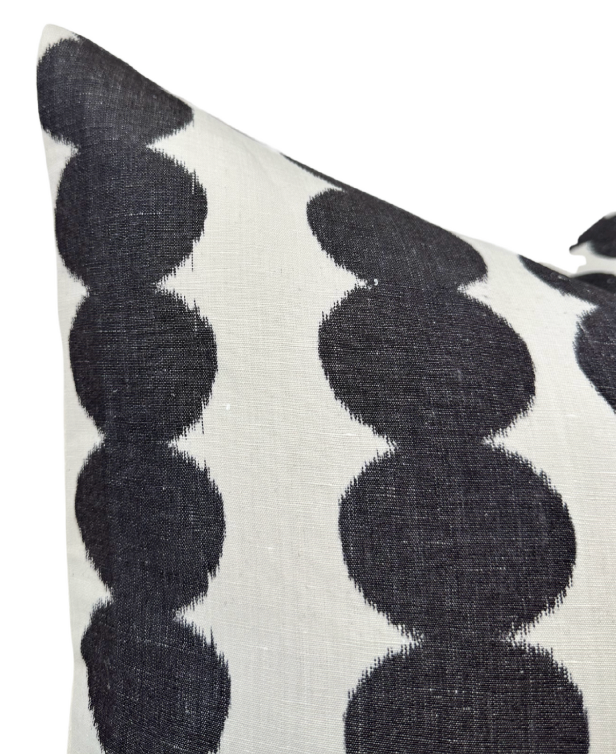 Close-up of a pillow cover featuring a pattern of large black circular shapes linked vertically on a white textured fabric background.