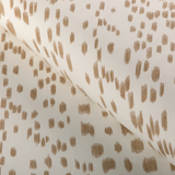 Close-up of a beige fabric with scattered, irregular vertical dash patterns in sand color, showing texture and soft folds.