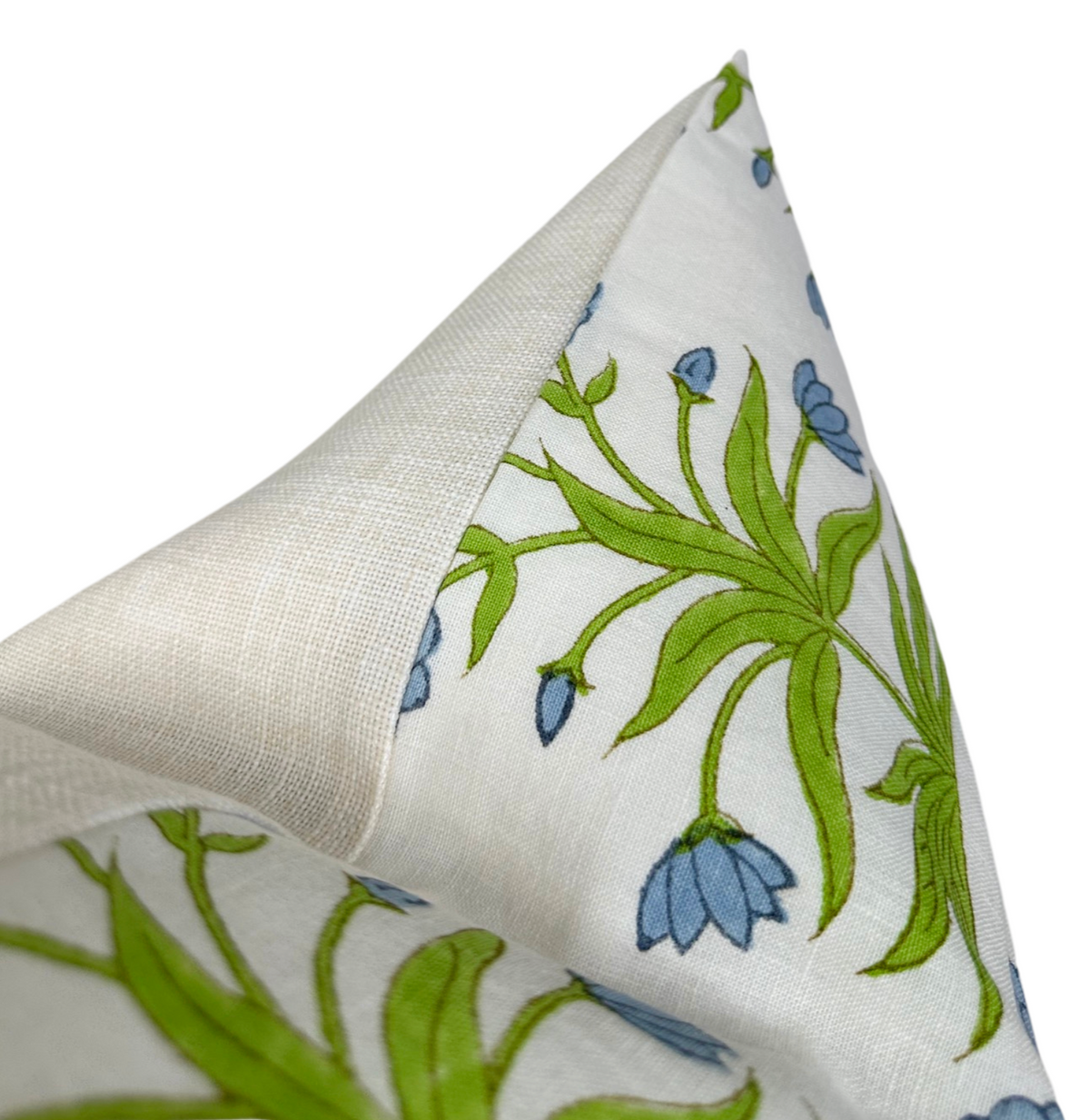 Close-up of a pillow corner featuring a white fabric with green leafy vines and light blue floral buds in a delicate Mughal-inspired pattern, folded to show a plain textured back.