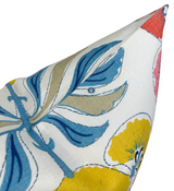 Close-up of a pillow cover featuring bold blue leaves with black outlines and yellow floral accents on a white fabric background.