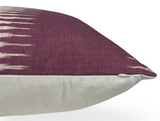 Side view of an ikat pillow cover with deep purple upper fabric featuring white geometric streaks and a solid off-white bottom section with a hidden zipper.