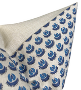Corner of a pillow cover with beige fabric on one side and a blue floral pattern on the other in varying blue shades against a light background.