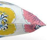 Close-up of a pillow corner showing coral and yellow floral patterns with navy and light blue accents on white fabric and a covered zipper seam.
