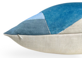 Close-up of a geometric-patterned pillow cover featuring navy, cerulean, and light blue triangles above a natural beige fabric base, with a subtle white zipper detail.