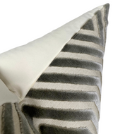 Close-up of a pillow cover with a dove grey velvet geometric stripe pattern on a textured fabric background and a solid light grey backing.
