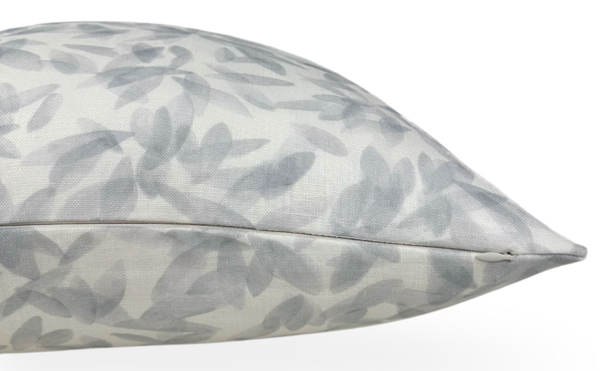 Side view of a pillow with light gray abstract leaf patterns on a white background and a neatly finished edge seam.