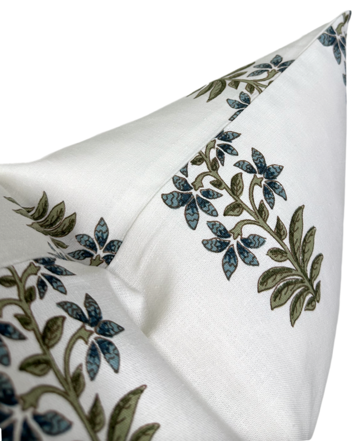 Close-up of a white pillow cover featuring green and indigo floral patterns with leafy stems, highlighting its sharp corner and fine textile texture.
