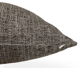 Close-up of a chestnut-colored performance pillow cover with a textured, woven pattern and a visible white zipper pull on its edge.