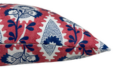 Close-up of a red pillow cover featuring white and navy blue floral patterns with leafy branches, highlighting the fabric texture and detailed stitching along the edge.