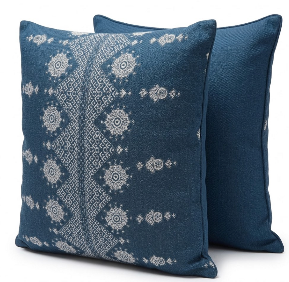 Two square pillows in deep indigo, one with white geometric and floral patterns forming vertical bands, the other solid indigo with matching piping edges.