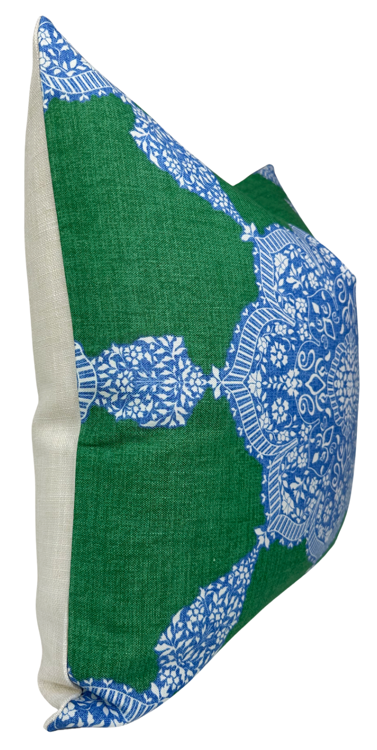 Rectangular pillow cover with a blue and white medallion pattern on a green background and natural beige fabric on the sides, shown at an angle.