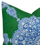 Close-up of a green pillow cover featuring an intricate blue and white floral medallion pattern with striped accents on textured fabric.