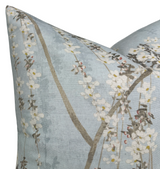 Blue pillow cover with a delicate print of cascading white blossoms and slender brown branches, creating a soft, nature-inspired design.