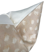 Close-up of a beige ivory pillow cover featuring a subtle feline spot pattern with a smooth white fabric border at the corner.