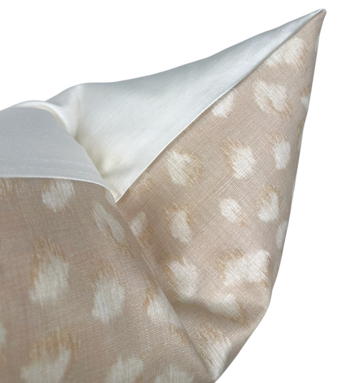 Close-up of a beige ivory pillow cover featuring a subtle feline spot pattern with a smooth white fabric border at the corner.