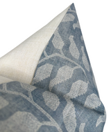Close-up of a pillow cover showing a textured leaf pattern in lake blue and beige on fabric with a visible seam and a contrasting light beige corner flap.