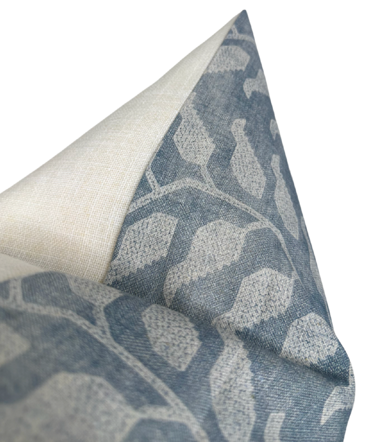 Close-up of a pillow cover showing a textured leaf pattern in lake blue and beige on fabric with a visible seam and a contrasting light beige corner flap.