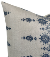 Close-up of a decorative pillow cover in natural fabric with indigo geometric and floral motifs arranged in a repeating pattern.