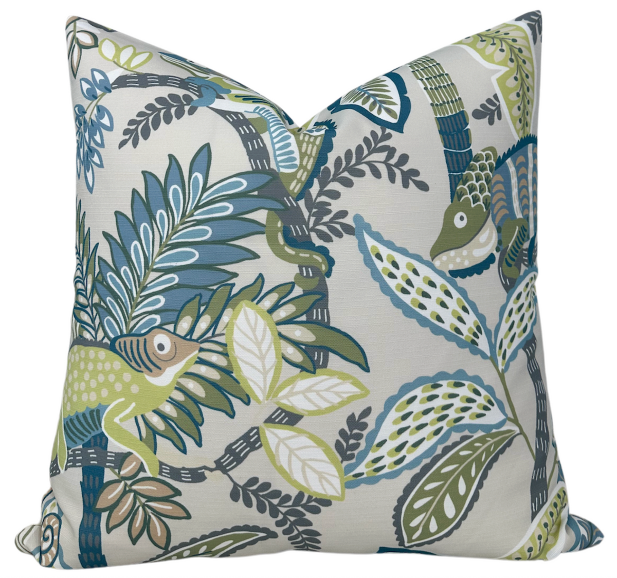 Square pillow with a botanical and chameleon pattern in shades of blue, green, and beige on a light background, showcasing leaves and two chameleons.