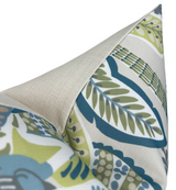 Corner of a pillow with a cream-colored linen back and a front displaying a leafy pattern in blue, green, and gray tones on white fabric.