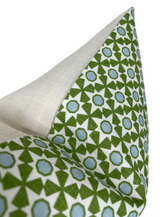 Pillow corner showing a green and blue geometric pattern on white fabric with a natural beige linen reverse side.
