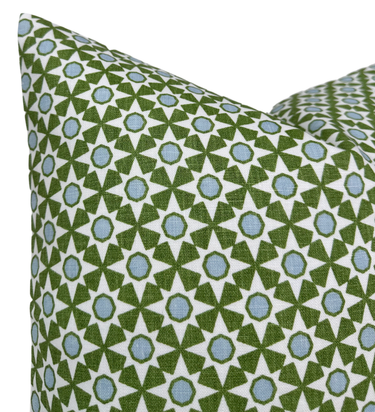 Square pillow with a repeating geometric pattern of green star shapes and blue circles on a white background, shown in close-up.