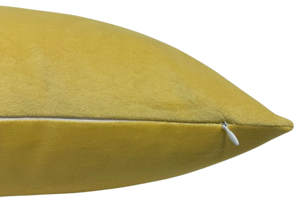 Close-up of a canary yellow velvet pillow cover with a white zipper on one edge, showing smooth textured fabric and clean stitching.