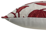 Close-up of a beige pillow with dark red botanical floral patterns and a visible zipper along one side seam on a light gray background.