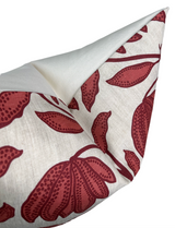 Close-up of a pillow cover showing burgundy floral and leaf patterns on a cream background with a folded corner revealing a plain white reverse side.