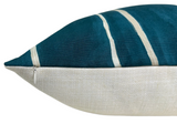 Corner of a rectangular pillow with teal fabric and white curved stripes on top, featuring a visible white zipper along the edge, and a textured off-white fabric on the bottom.