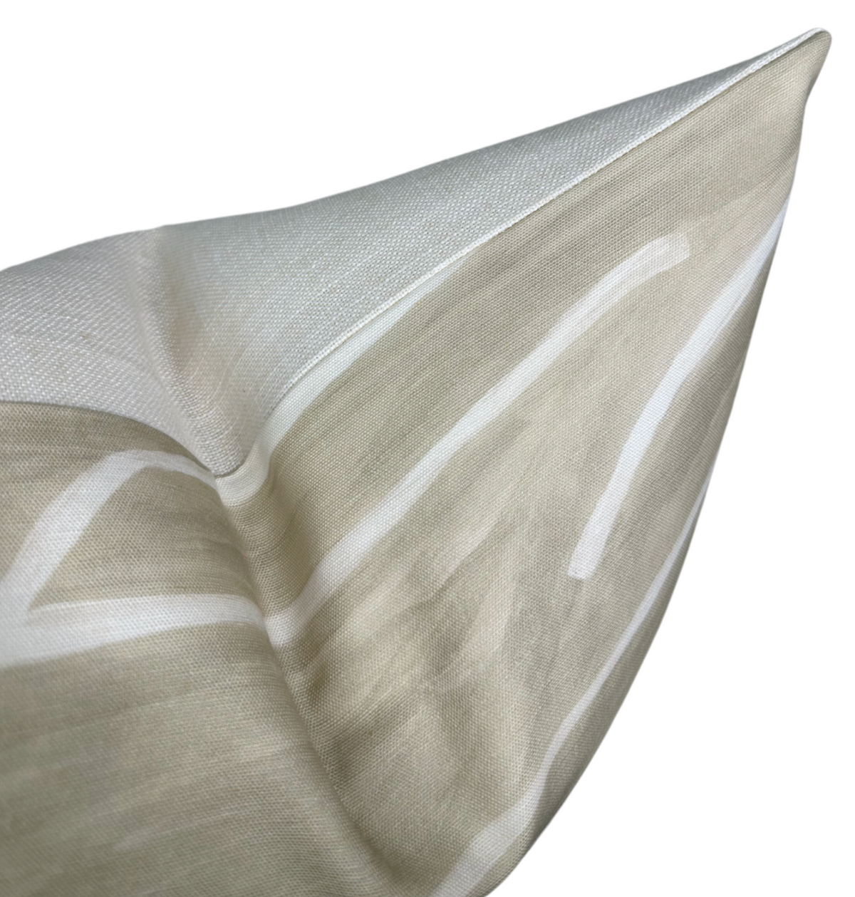 Close-up of beige and ivory pillow cover with abstract white graffiti-like lines on textured fabric, shown from an angled perspective highlighting the corner.