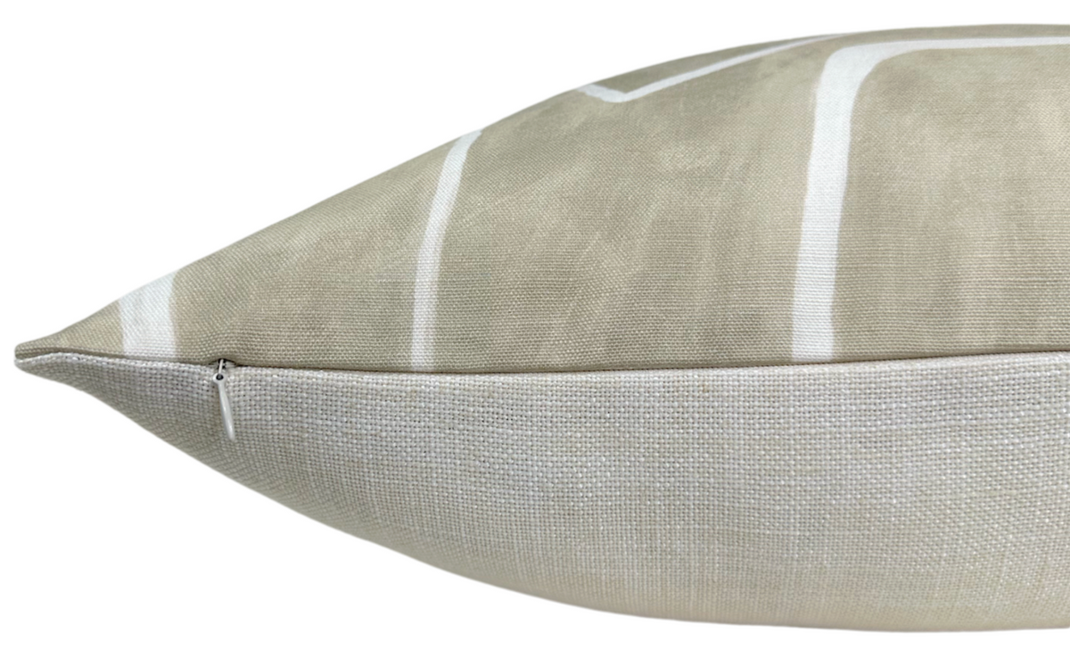 Close-up side view of a beige and ivory pillow cover with a subtle vertical stripe pattern and a visible zipper along the edge.
