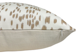 Side view of a sand-colored pillow cover featuring textured beige fabric on the bottom and white fabric with scattered brown dot patterns on top, showing a visible zipper.