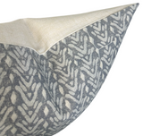 Close-up of a pillow cover corner with a beige top panel and a gray patterned lower panel featuring abstract leaf shapes in cream on the sides.