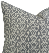 Corner view of a pillow cover featuring a repeating abstract geometric pattern in dark gray and off-white tones, with visible texture on the fabric.