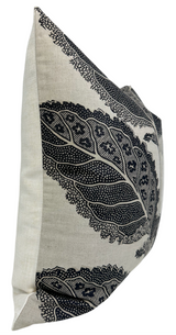 Side view of a square pillow with beige fabric and black intricate lace-like leaf patterns forming a bold, detailed border design.