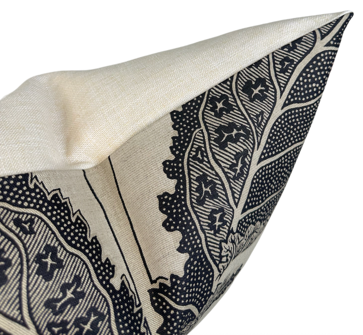 Close-up of a beige pillow cover with a bold black botanical print featuring detailed leaves and star shapes on a linen-like fabric.
