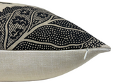 Close-up of a pillow corner showing black patterned fabric with botanical and dotted designs on a beige background, featuring a small white zipper.