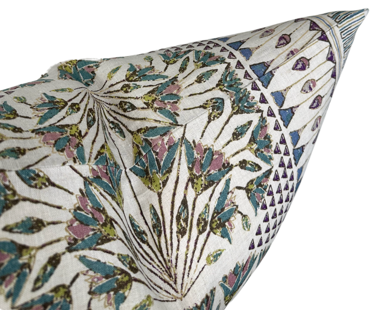 Close-up of pillow corner featuring intricate floral and geometric patterns in muted eggplant purple, teal, olive green, and white threads on textured fabric.