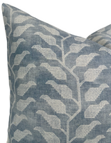 Close-up of a pillow cover in muted lake blue with an off-white geometric leaf pattern, showing textured woven fabric detail and sharp corner stitching.